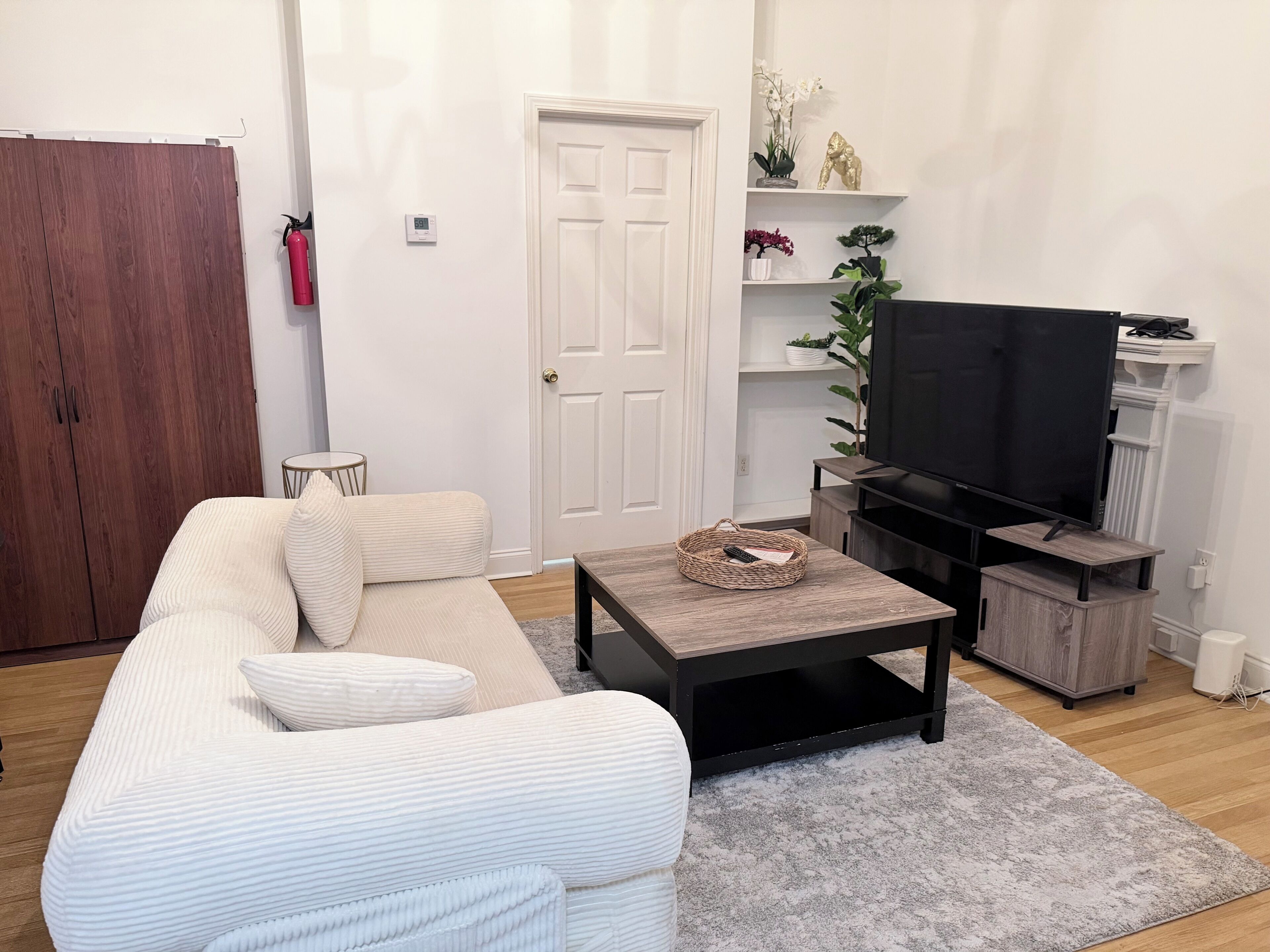 A living room with a sofa, a coffee table, a television, and a bookshelf.
