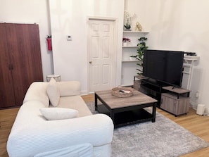 A living room with a sofa, a coffee table, a television, and a bookshelf. - Perfect 1-bedroom apartment (Doraville)