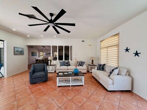 A living room with a ceiling fan, a white sofa, a patterned armchair, and a coffee table. - Waterfront Oasis: A peaceful escape in Cape Coral (Cape Coral)