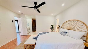 Un dormitorio con cama, ventilador de techo, mesita de noche y tocador.