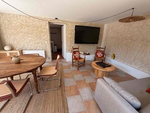 A living room with a dining area, a flat-screen TV mounted on the wall, and a sofa. - House in Vetheuil with private pool near Giverny and Roche Guyon (Vétheuil)