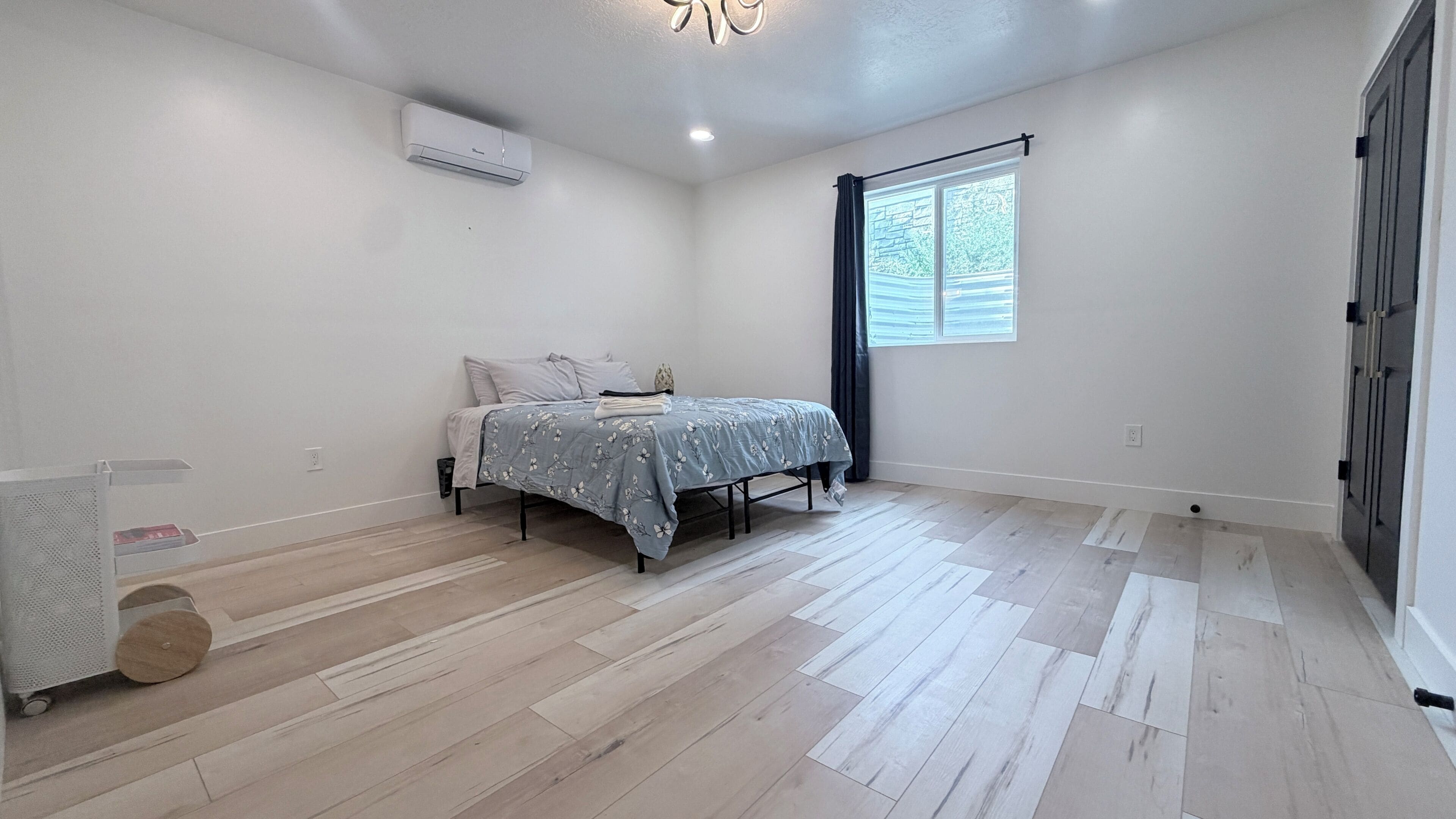 A bedroom with a bed, a window, and an air conditioning unit.