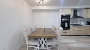 A modern kitchen with a dining table and chairs, built-in appliances, and a clean, minimalist design. - Luxury Living @ SLC/Airport Ski/Hike/EV Charging - 5 Bed 5 Bath (West Valley City)