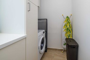 A laundry area with a washing machine, a drying rack, and a trash bin. - Holiday house VILLA OLIVA with pool (Poljica)