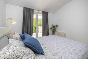 A bedroom with a bed, a lamp, a potted plant, and a view of the outdoors. - Holiday house VILLA OLIVA with pool (Poljica)