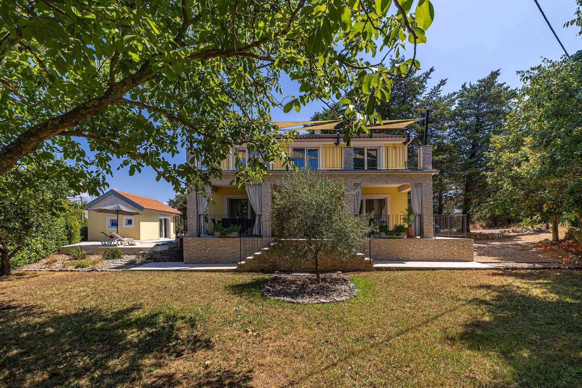 A two-story house with a balcony, a small garden, and a clear sky.