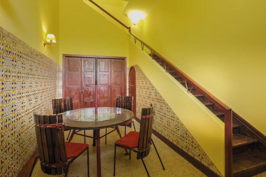 A dining area with a round table and chairs, a wooden door, and a staircase.