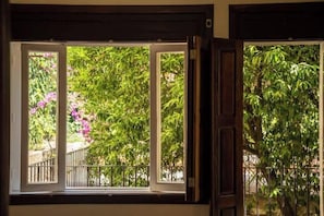 A window with a view of lush greenery and a balcony railing.