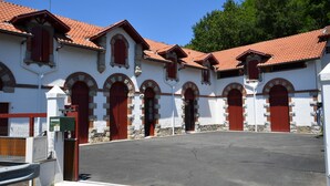 Ein Gebäude mit Innenhof, mit mehreren roten Türen und Rundbogenfenstern.