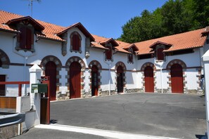 A building with a courtyard, featuring multiple red doors and arched windows. - One-Bedroom Apartment for Rent in the Heart of the Basque Country (Cambo-les-Bains)