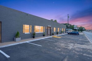 A building with a flat facade, a gated entrance, and a parking lot with marked spaces. - 2BR Apt Retreat Gated Downtown Killeen (Killeen)