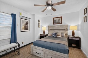 A bedroom with a bed, bedside tables, a ceiling fan, a window with curtains, and wall-mounted artwork. - 2BR Apt Retreat Gated Downtown Killeen (Killeen)