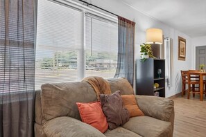 A living room with a sofa, a lamp, a plant, and a dining area with a table and chairs. - 2BR Apt Retreat Gated Downtown Killeen (Killeen)