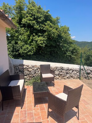An outdoor patio with wicker furniture and a stone wall backdrop. - Podere la Terrazza - Three-room apartment with pool and hot tub (Prata)