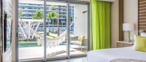 A hotel room with a large bed, a view of a pool area, and a sliding glass door.