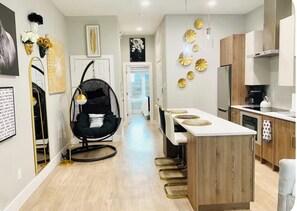 A modern kitchen with a central island, wooden cabinets, and a black chair. - 2 Beds Near Downtown, Stockyards, Zoos, Sundance, 6 Flags,AT&T Stadium, Botanic (Fort Worth)