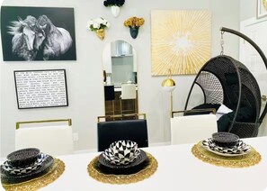 A dining area with a white table, black and white patterned centerpieces, a black hanging chair, and a mirror above the table. - 2 Beds Near Downtown, Stockyards, Zoos, Sundance, 6 Flags,AT&T Stadium, Botanic (Fort Worth)