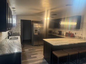 Eine moderne Küche mit einem Edelstahl-Kühlschrank, einer Mikrowelle und einer Kaffeemaschine auf der Arbeitsfläche.