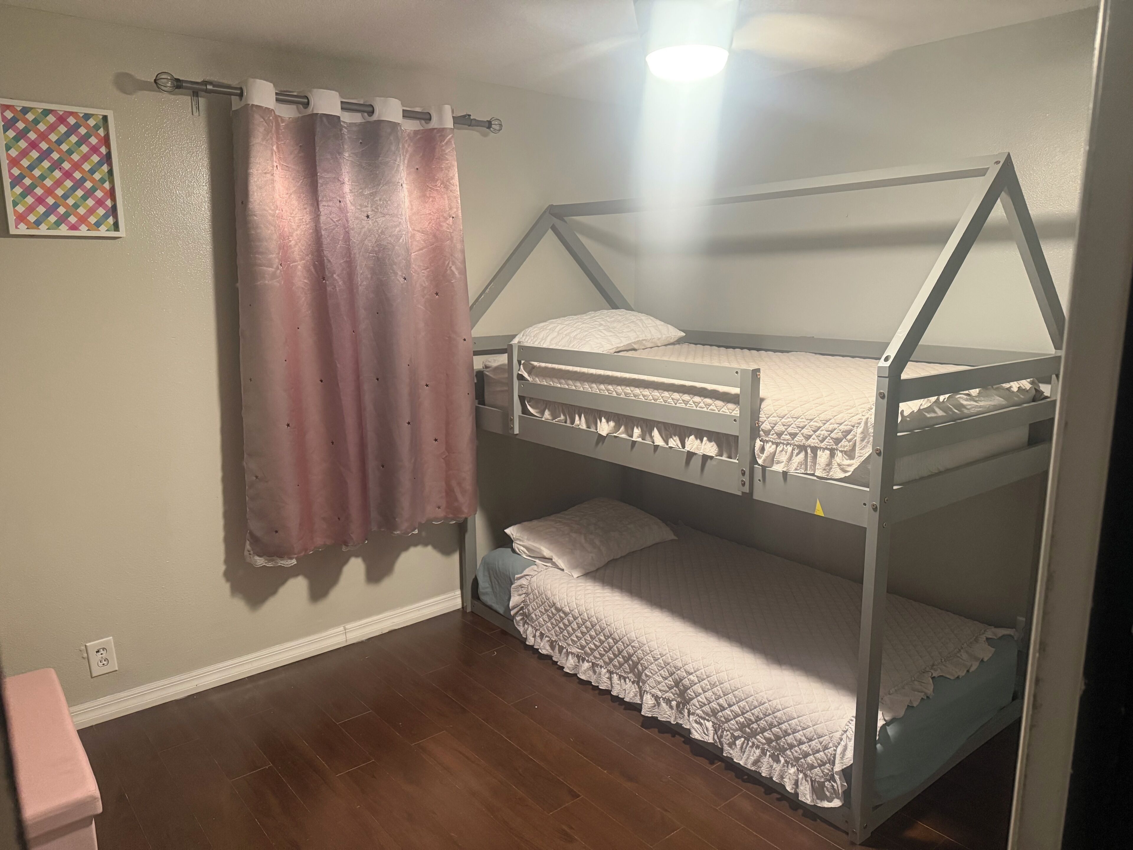 Habitación con literas, un enchufe y un adorno de pared con diseño.