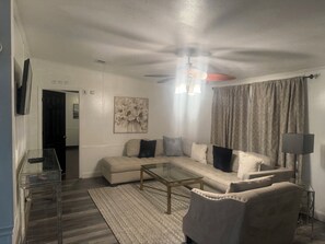 Ein Wohnzimmer mit Sofa, Couchtisch und Deckenventilator.
