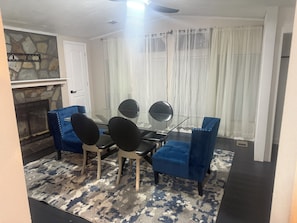 Ein Essbereich mit einem Glastisch, schwarzen Stühlen und einem blau gepolsterten Sofa.