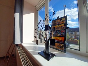 A window with a decorative metal tree and a framed cityscape view. - The Gemstone Manor (Watford)
