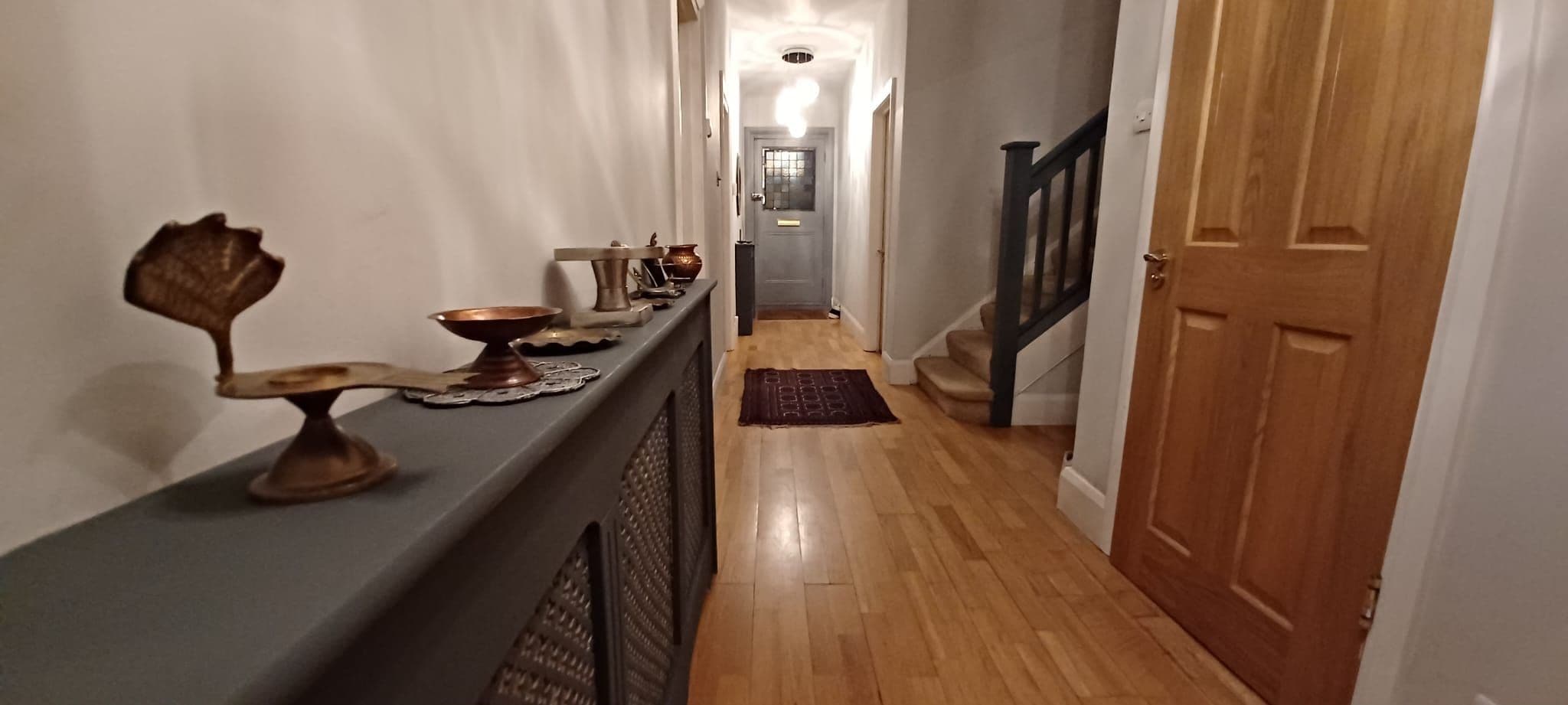 A hallway with a wooden floor, a dark blue counter, and a door on the right.
