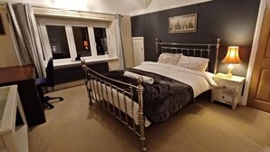 Et soveværelse med seng, sengebord, lampe, vindue og dør.