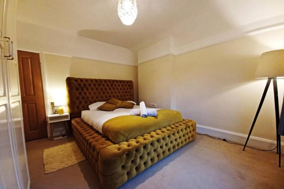Een slaapkamer met een groot bed, een nachtkastje, een lamp en een deur.