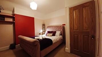 A bedroom with a bed, a wooden door, and a red wall.