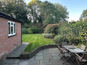 Ein Ziegelhaus mit kleinem Garten und Terrassenbereich.
