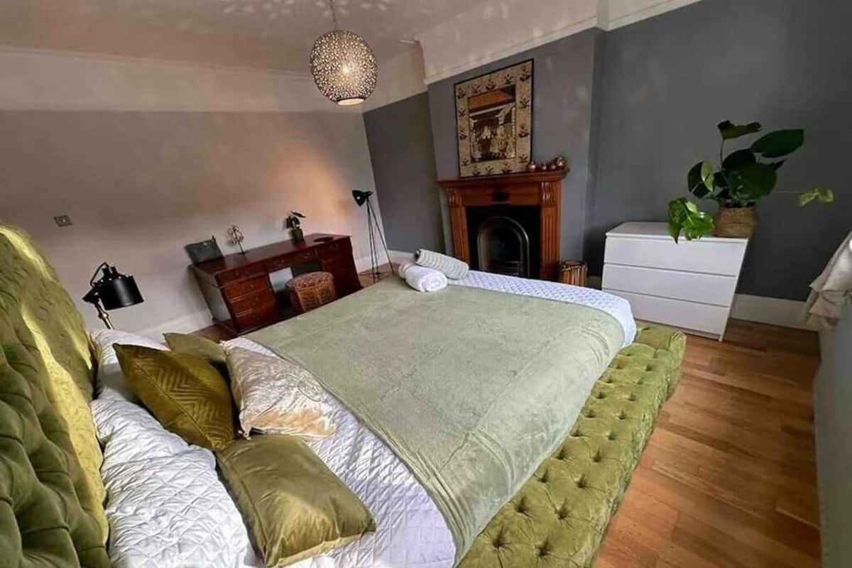 Een slaapkamer met een groot bed, een open haard, een bureau en een plant.