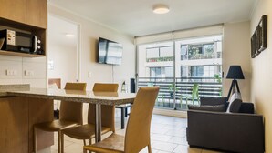 Eine moderne Küche mit Essbereich, einem an der Wand montierten Flachbildfernseher und einem Balkon mit Stadtblick.