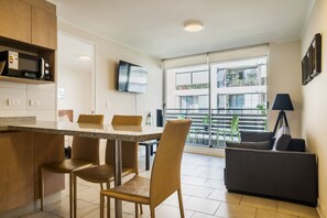 Eine moderne Küche mit Essbereich, einem an der Wand montierten Flachbildfernseher und einem Balkon mit Stadtblick.