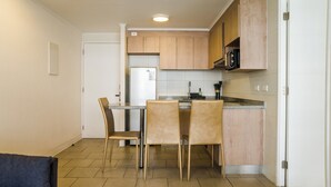 Eine kleine Küche mit Kühlschrank, Mikrowelle und Holzschränken.