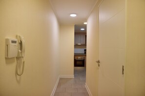 A narrow hallway with a telephone on the left and a door on the right.