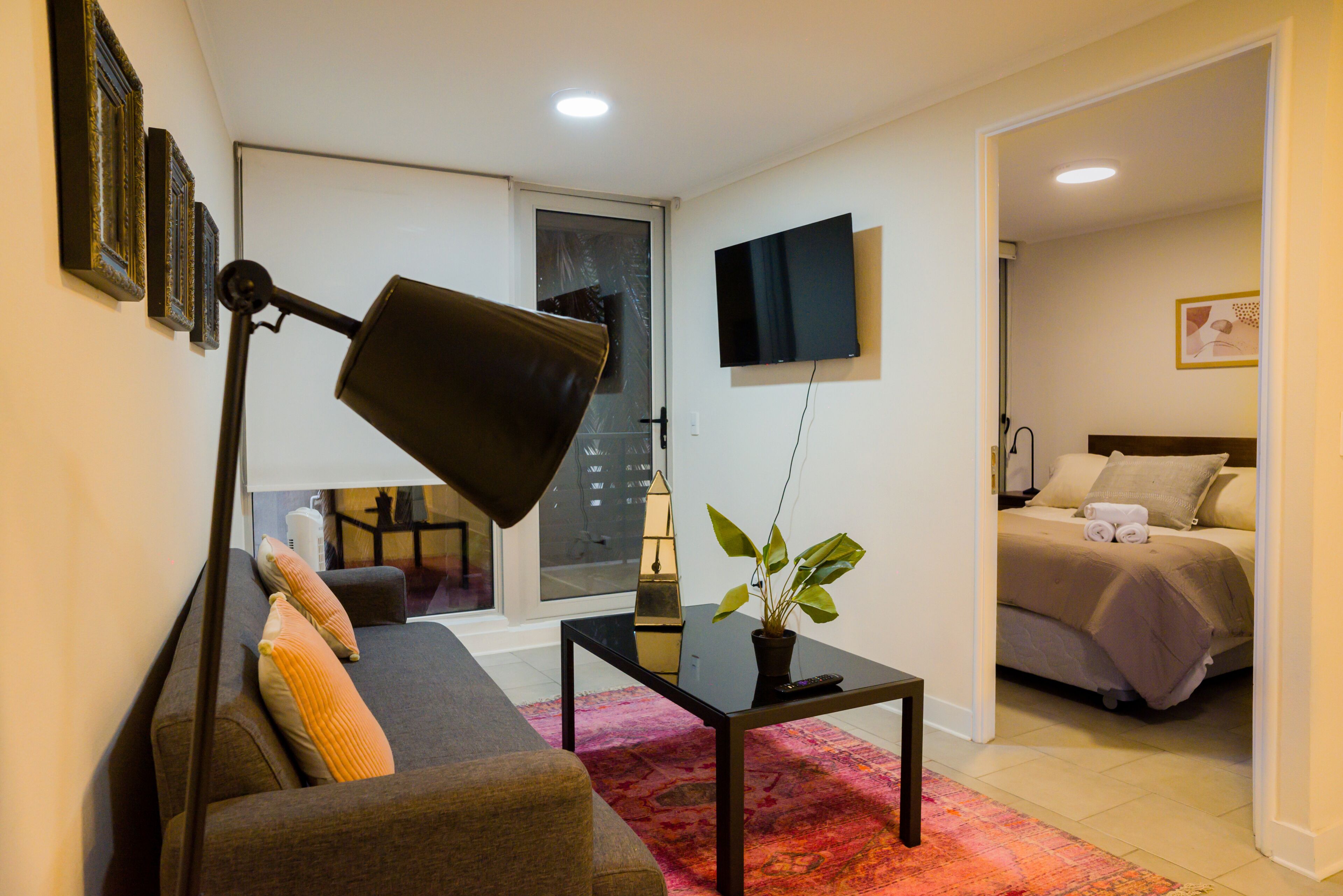 A modern living room with a sofa, a coffee table, a floor lamp, and a potted plant.