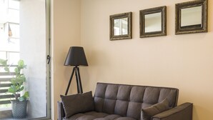 Ein Wohnzimmer mit grauem Sofa, einer Stehlampe und drei gerahmten Spiegeln an der Wand.