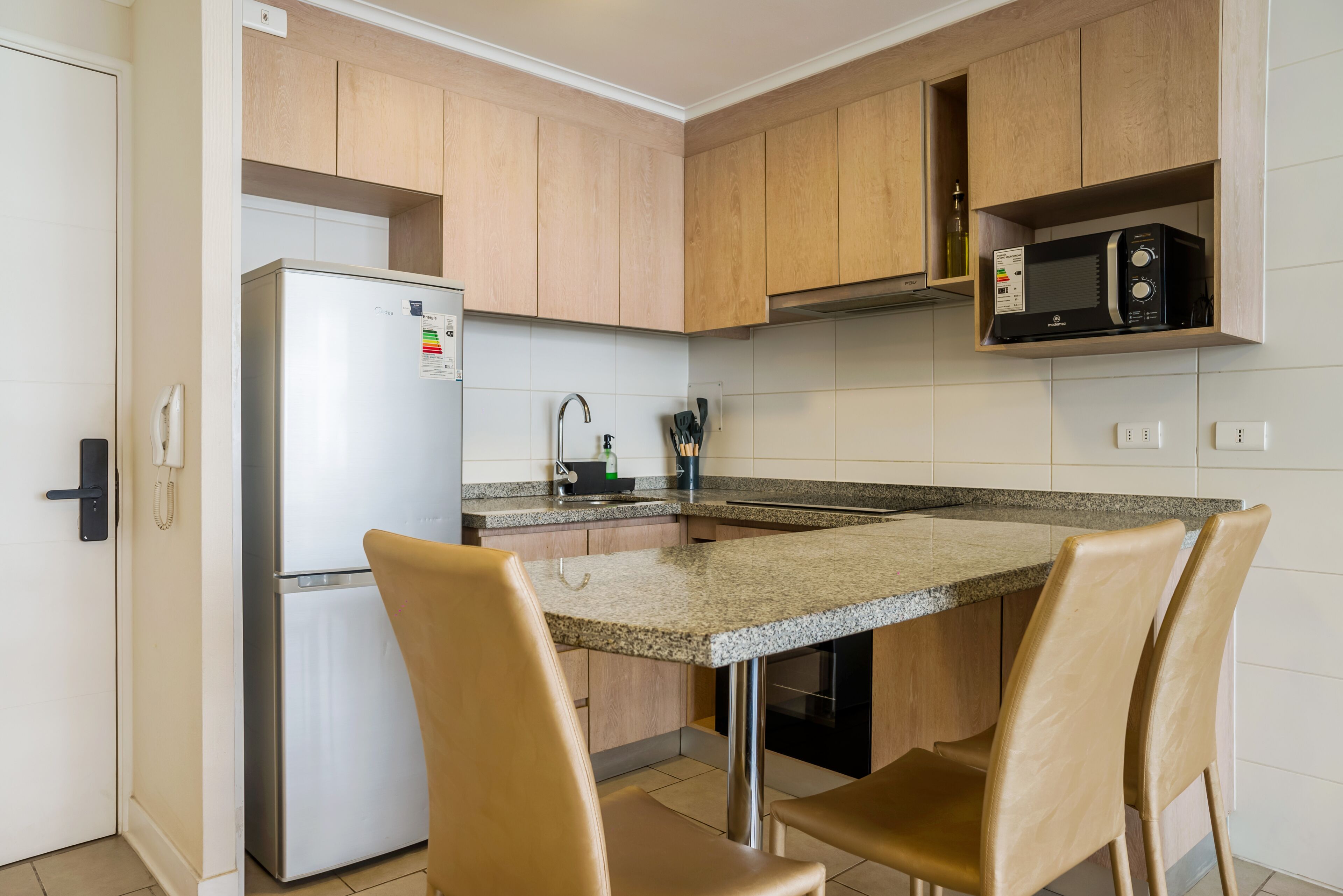 Una cocina funcional con refrigerador, microondas y una pequeña superficie de apoyo.
