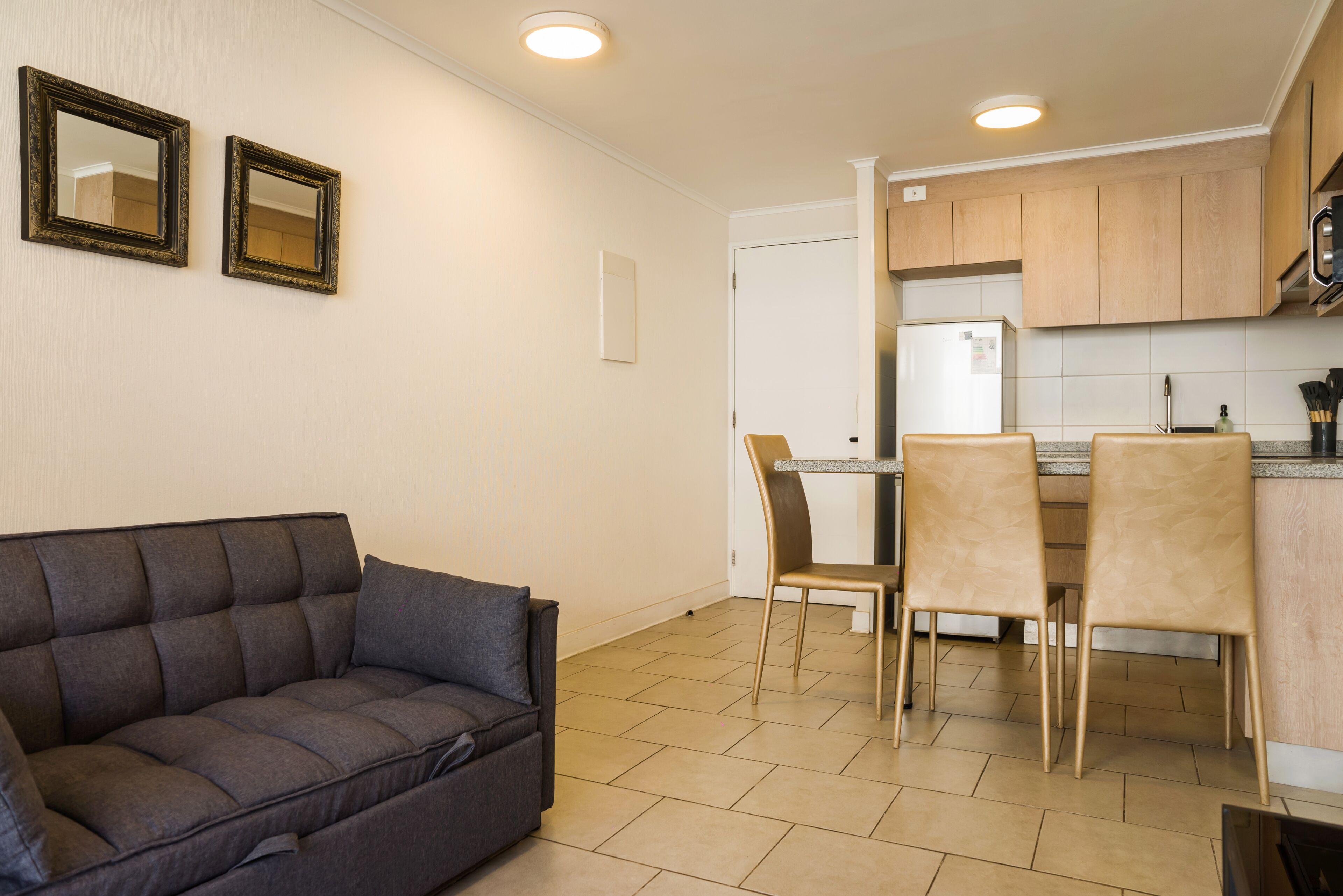 A compact living space with a sofa, dining table, chairs, and a kitchen area.