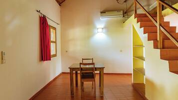 Una habitación con una mesa y una silla de madera, una cortina roja, una ventana y una escalera con escalones amarillos.