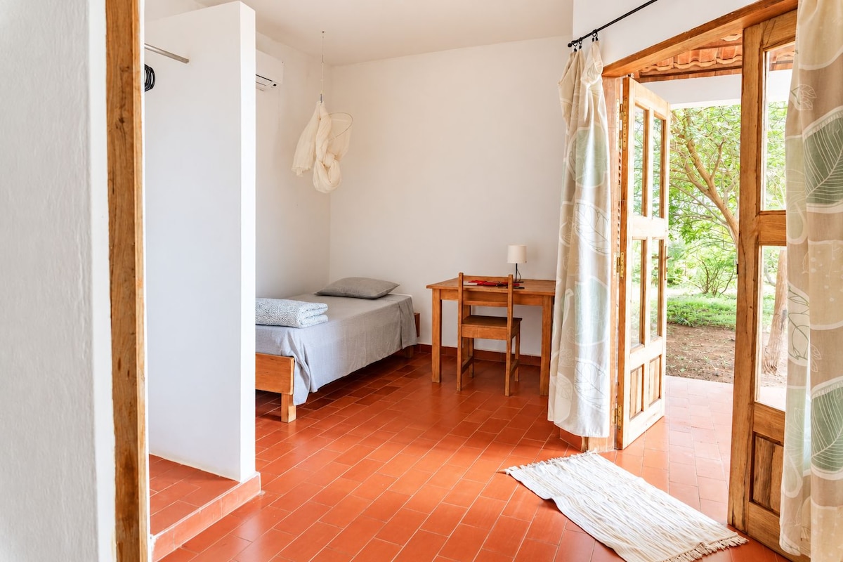 A room with a bed, a desk, and a view of the outdoors.
