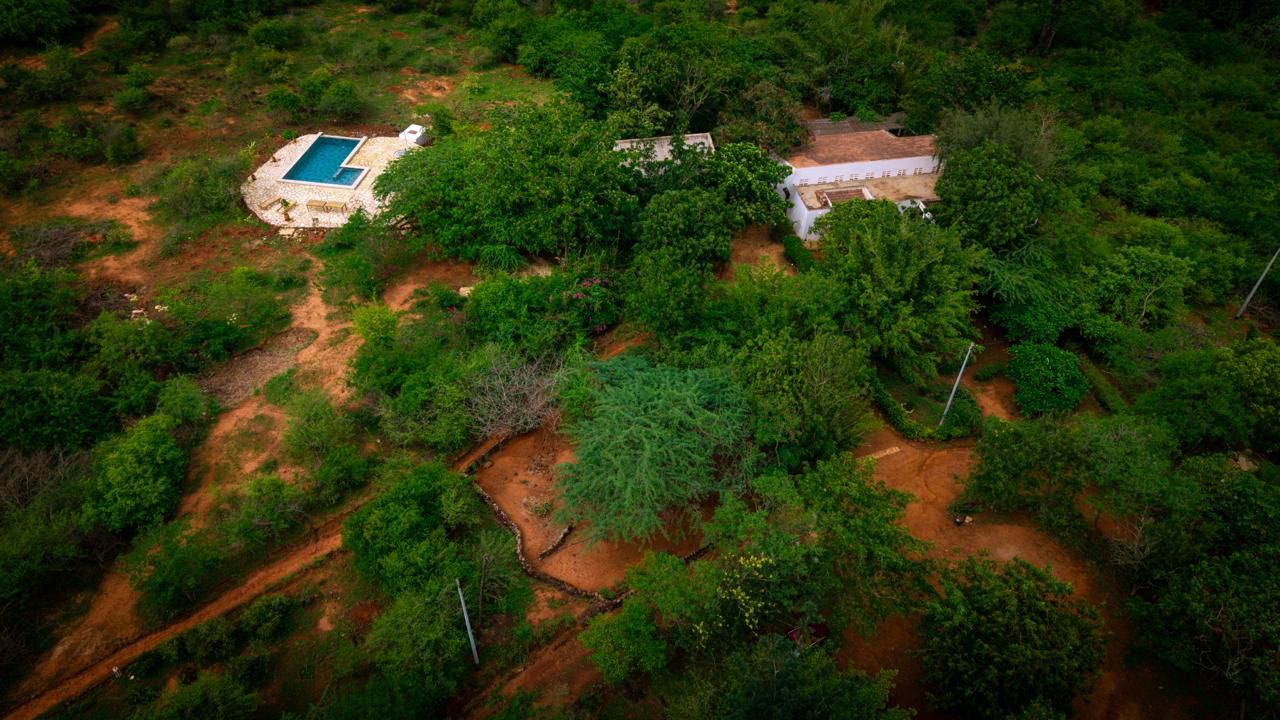 Vista aérea de una propiedad con piscina, edificio y vegetación circundante.