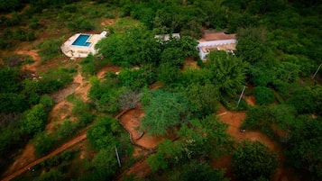Vista aérea de una propiedad con piscina, edificio y vegetación circundante.