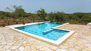 Ein rechteckiger Pool im Freien mit einer Terrasse aus Steinplatten.