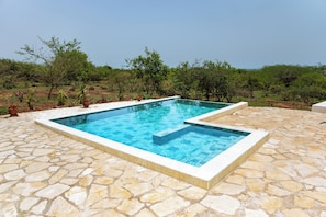 A rectangular outdoor swimming pool with a stone-tiled deck.