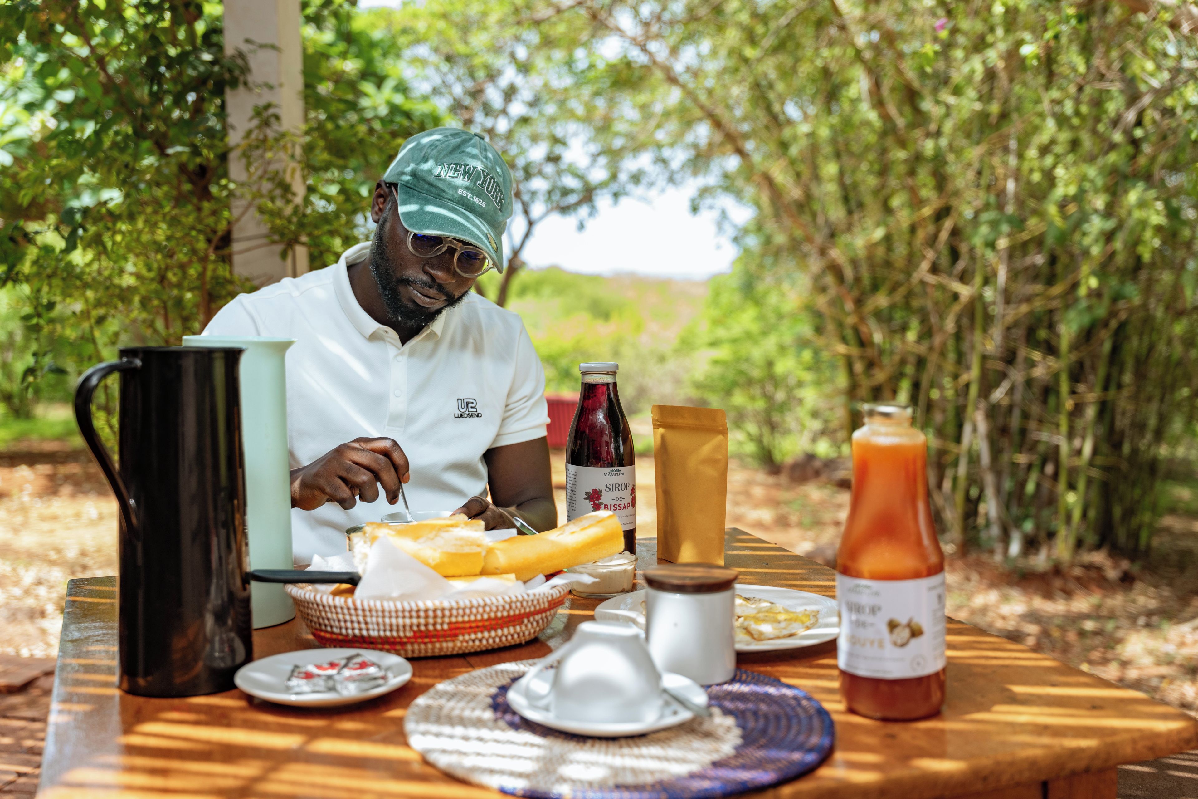 A person sitting at a table with a meal, a bottle of wine, and a jug of juice.