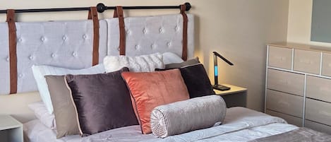 Ein Schlafzimmer mit einem Bett, einem Nachttisch, einer Lampe, einer Kommode und einem Deckenventilator.