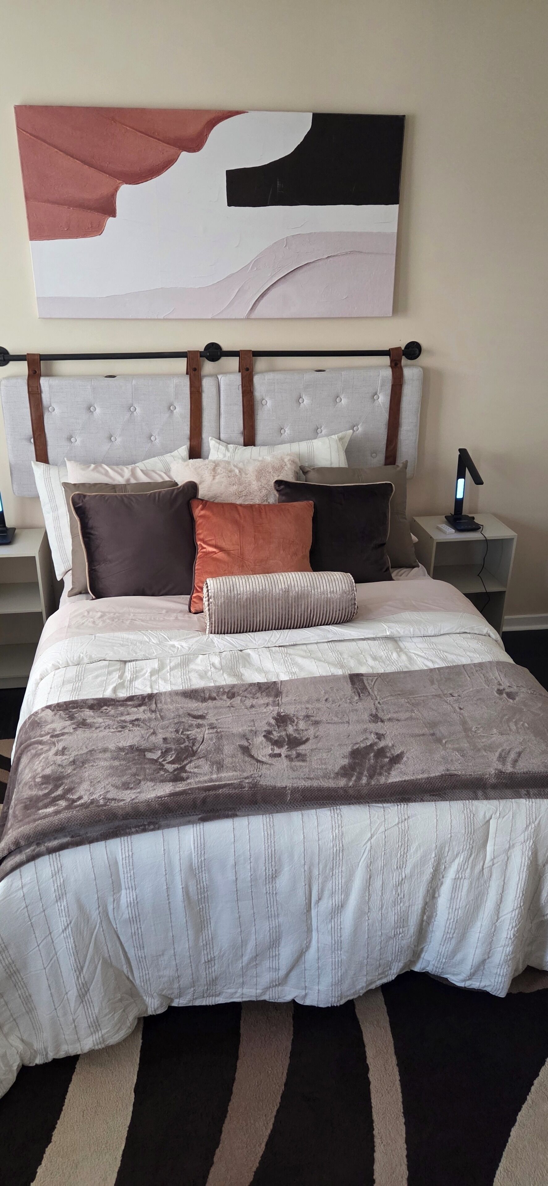 A neatly made bed with a patterned bedspread, a headboard with a tufted design, and a bedside table with a lamp.