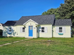 A two-story house with a blue door and white shutters, number 3355, with a grassy lawn in front.